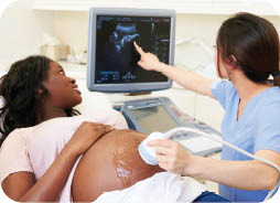 Pregnant woman getting a ultrasound, looking at the screen the technician is point at