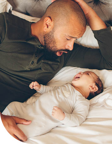 Dad and baby laying on bed and looking at each other