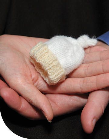 Two hands cradling a very small knit hat