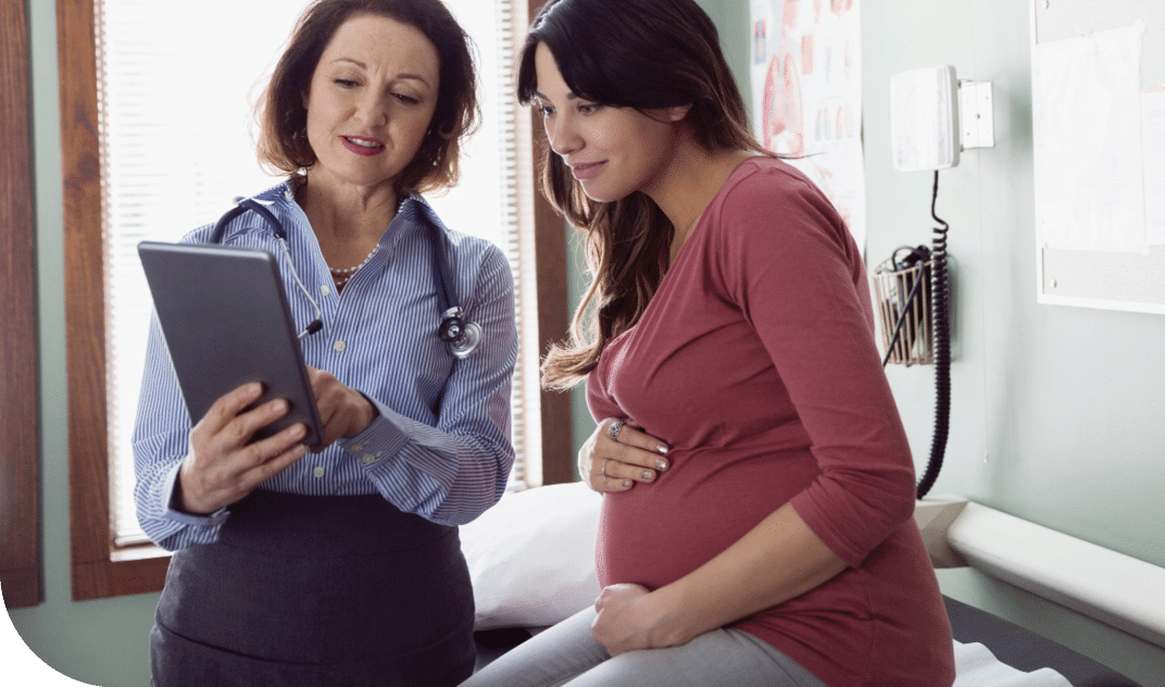 A pregnant woman at a doctor's appointment looking at a tablet that her doctor is showing her