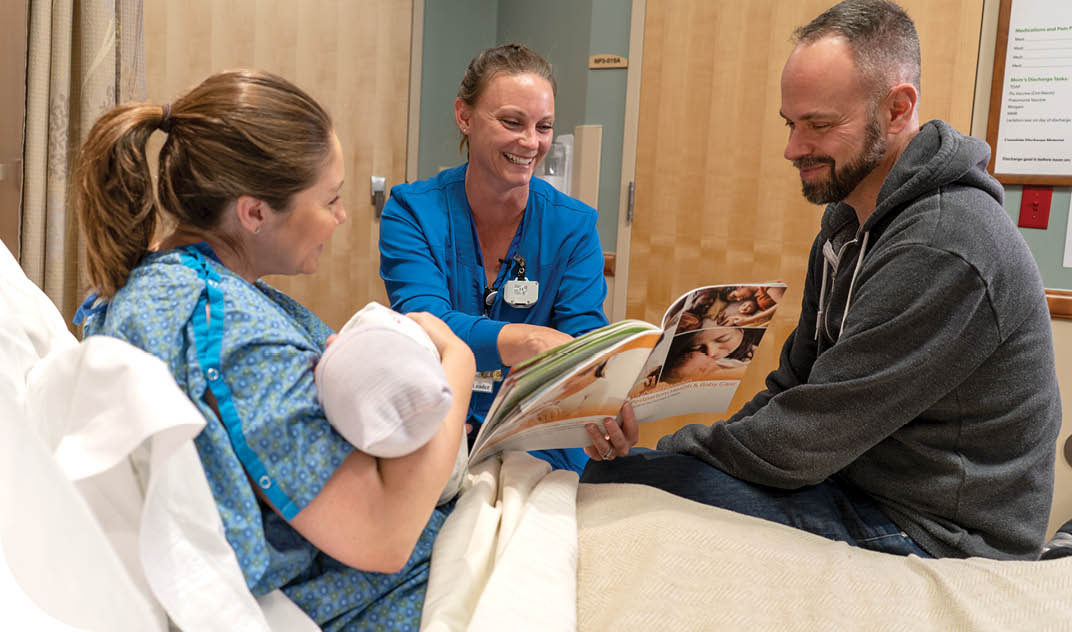 Family with newborn in hospital receving postpartum discharge instructions from nurse