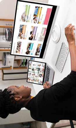 Woman sitting at a desk with a large screen and laptop to one side