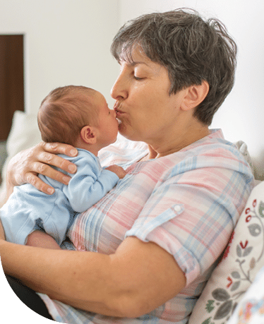 Grandmother holding baby grandchild and kissing them on the nose