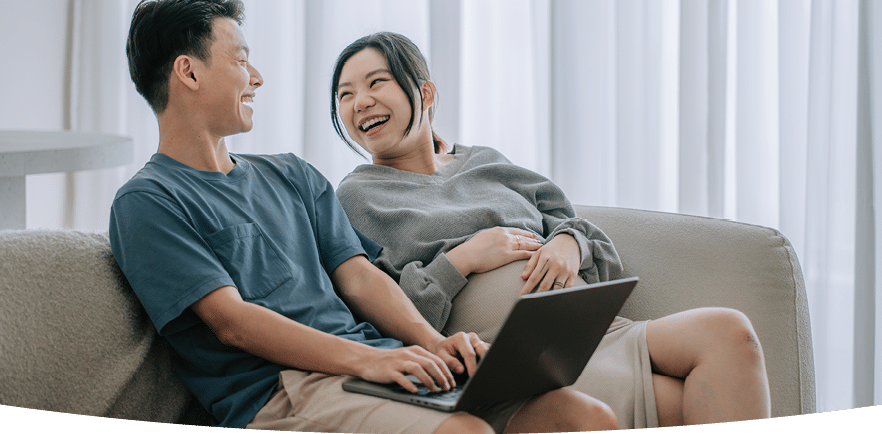 A man and woman are sitting on a couch, smiling and looking at a laptop. AI generated content